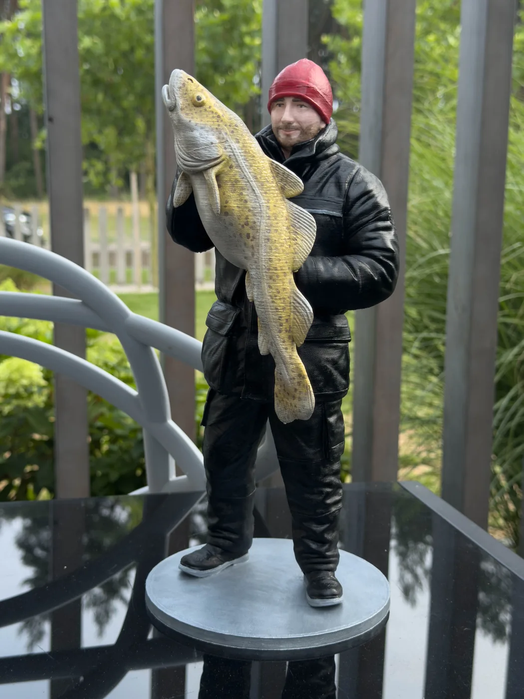 Realistyczna figurka mężczyzny w czerwonej czapce z dużą rybą, ujęcie z przodu - druk 3D